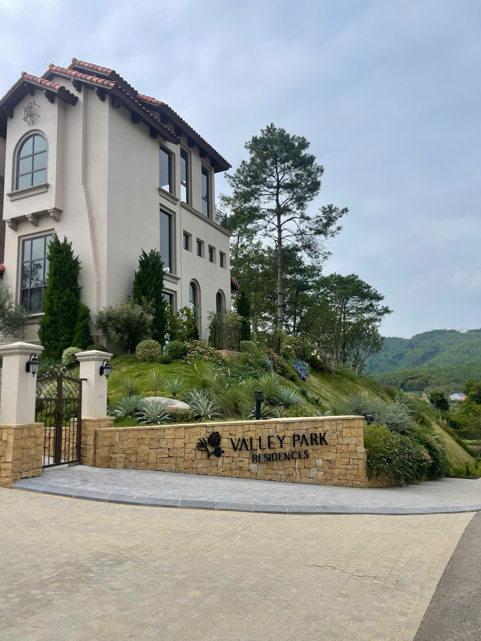 Cổng vào khu Valley Park Residences chụp thực tế năm 2024, cho thấy lối vào có cây xanh hai bên và kiến trúc cổng chính.